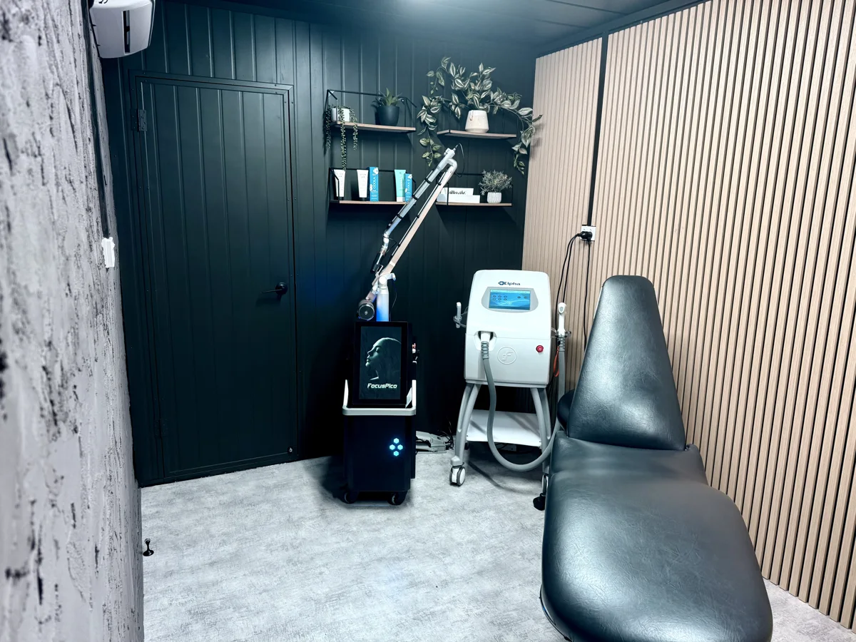 A finished Asylum laser treatment room with a dark wall, timber slats, treatment chair and laser systems